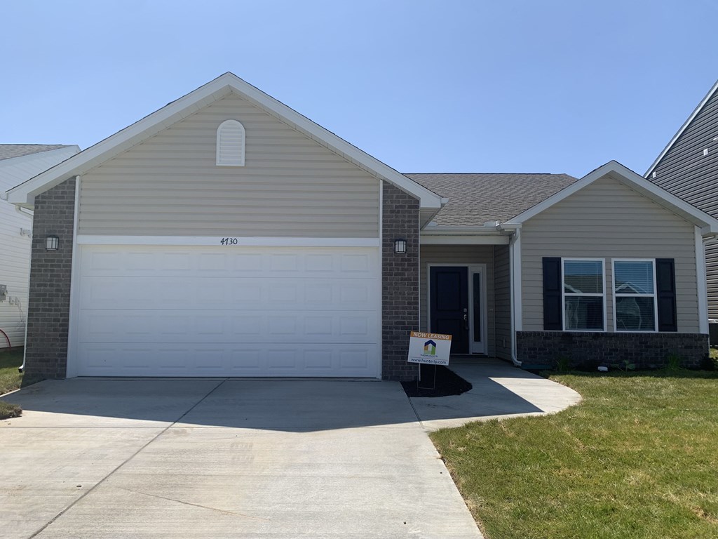 a house with a white garage door and a sign on the driveway
